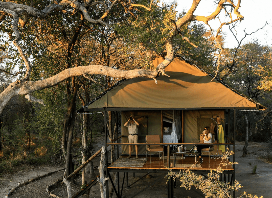  A couple are on the terrace of a safari camp tent. 