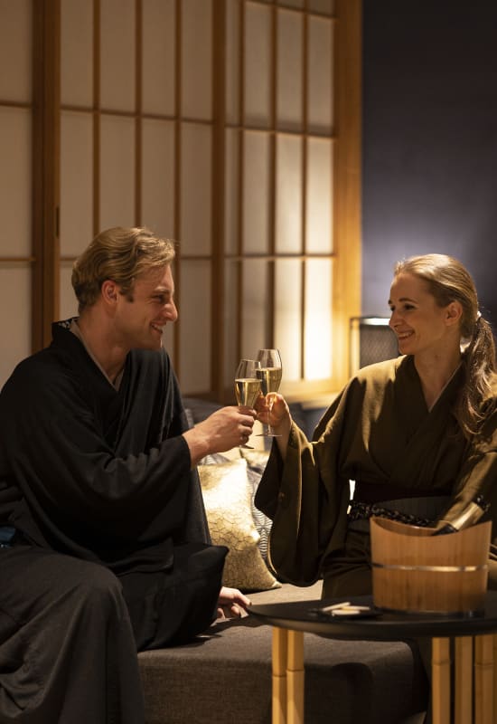 Two guests enjoy some prosecco as they sit in their guest room.