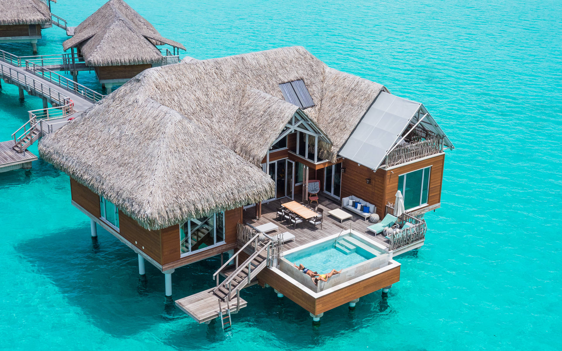 An overwater villa has two levels, a pool and an outdoor sitting area. 
