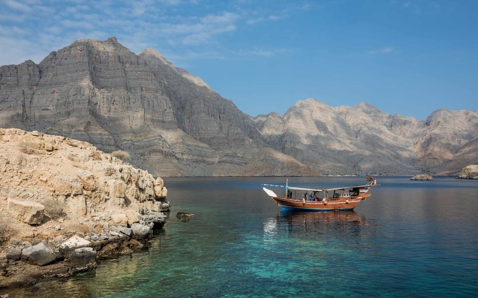 A Dhow Boat glides across the clear waters of the Musandam Peninsula.