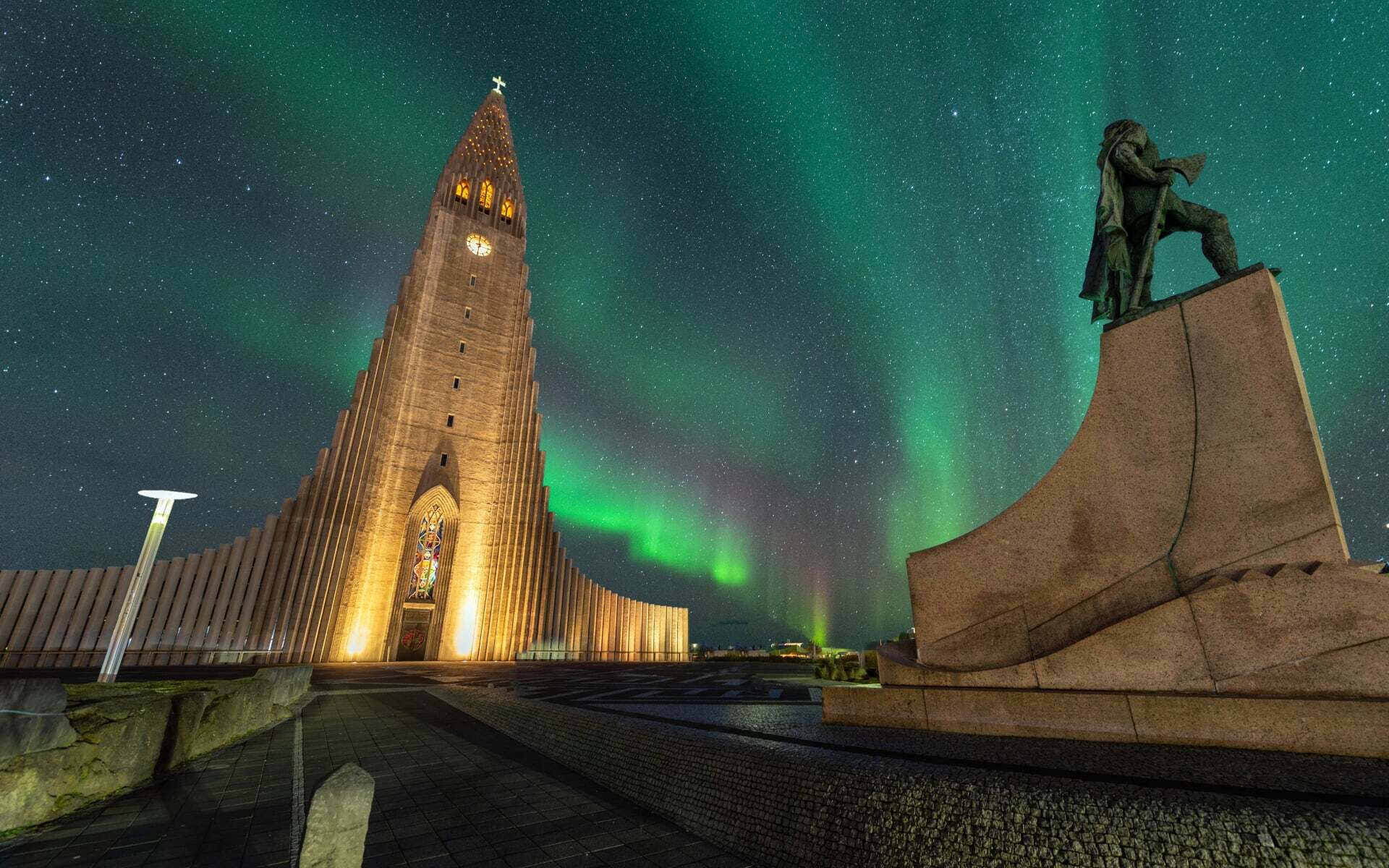 Hallgrímskirkja Church in Reykjavik glows ahead of the Aurora Borealis