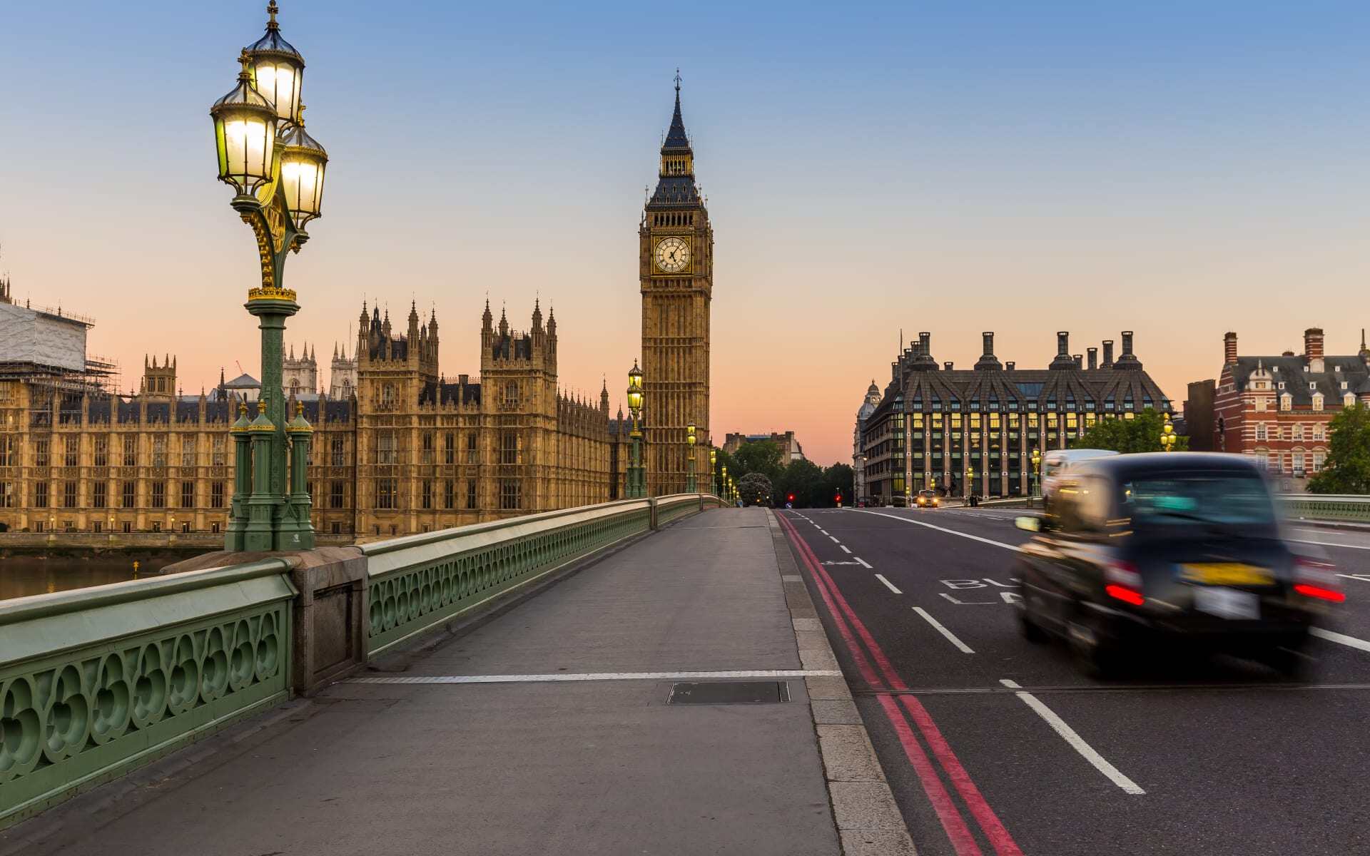 A black taxi whizzes along Westminster Bridge in London.