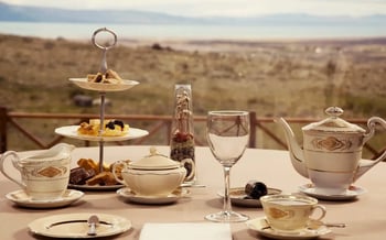 An afternoon tea is lain out on a table ahead of a sweeping, grassy view of Patagonia.