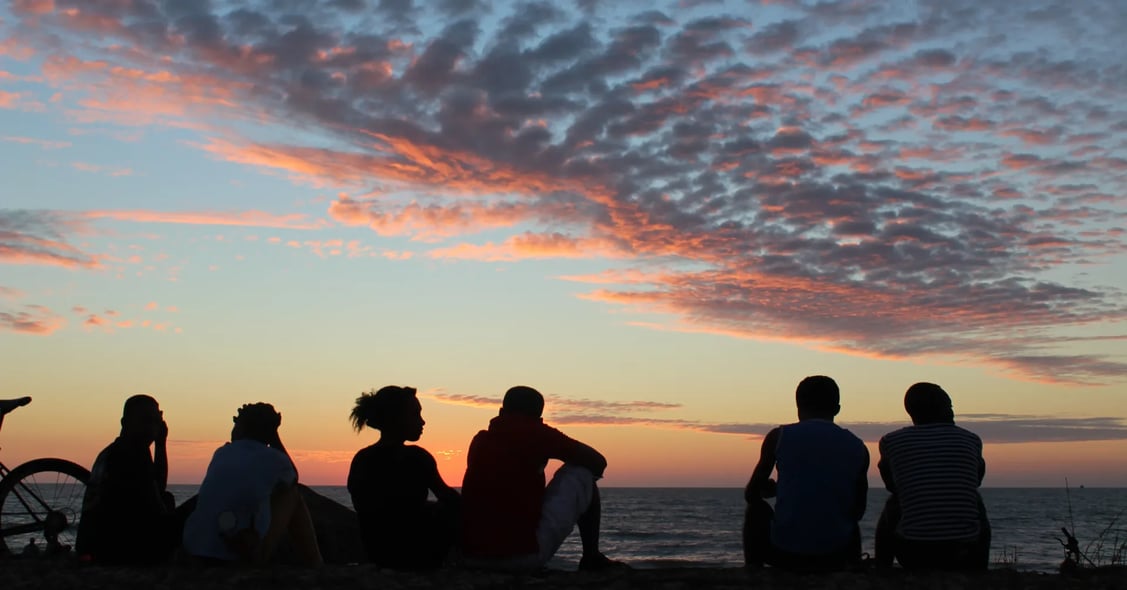 Some friends enjoy a holiday in Madagascar as they sit on a beach during sunset