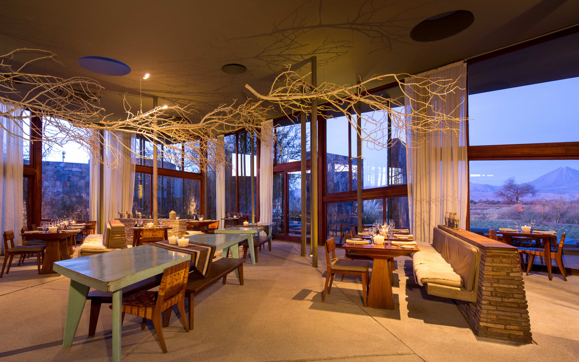 The restaurant at Tierra Atacama has floor-to-ceiling windows and wooden tables that match its earthy exterior.