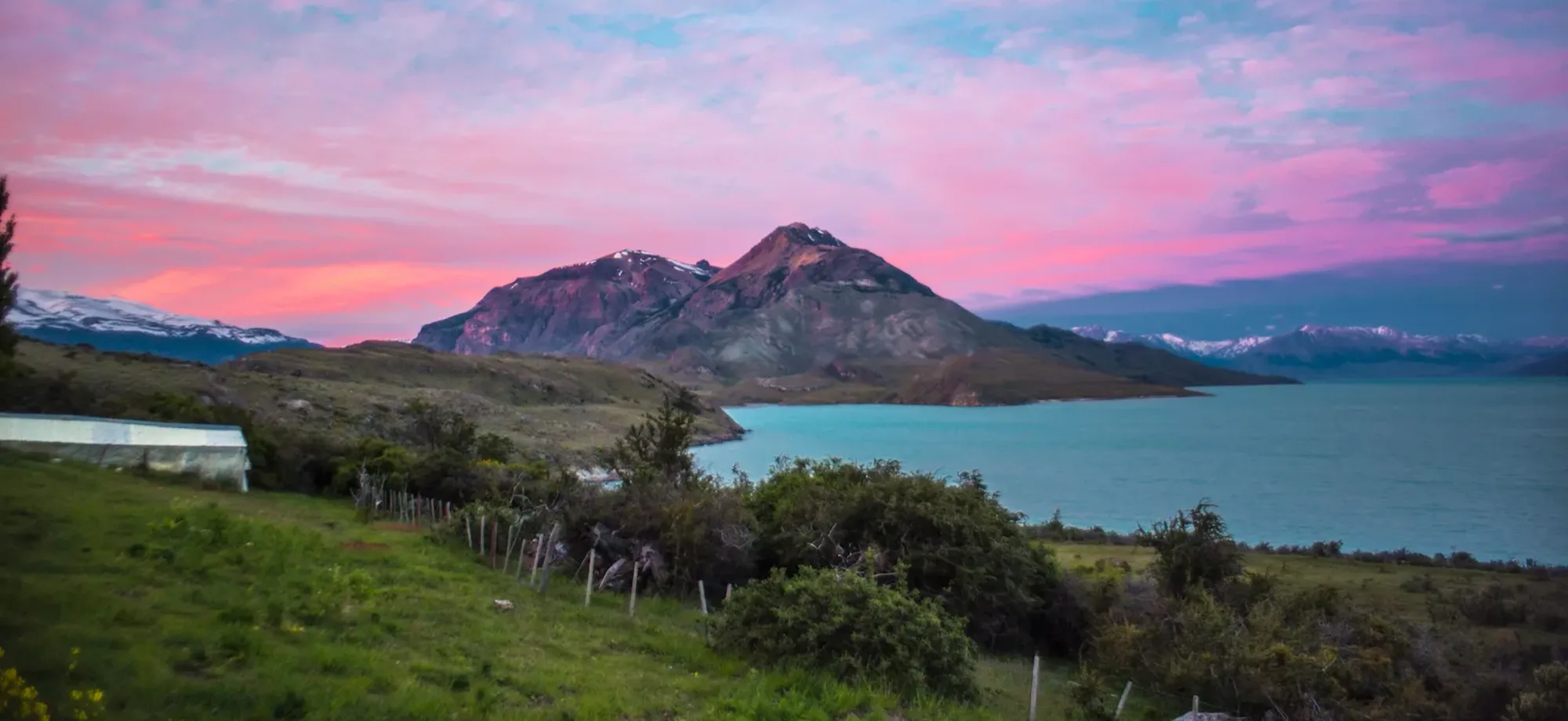 A sunset scene of Lake San Martin is completed by the tumbling Andes and the lush green of the estancia's gardens.