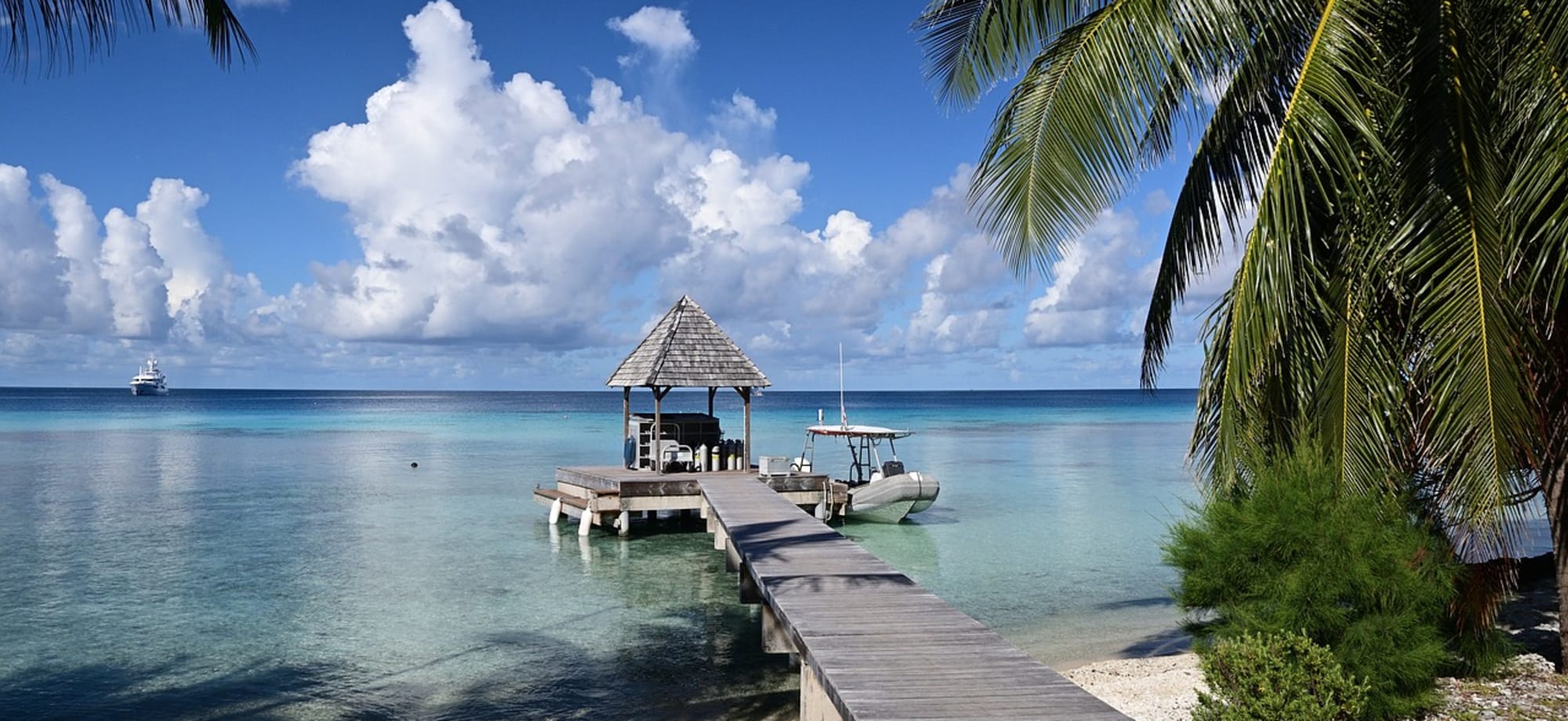 A hut sits above the ocean and is surrounded by palm trees and a beach in Rangiroa.