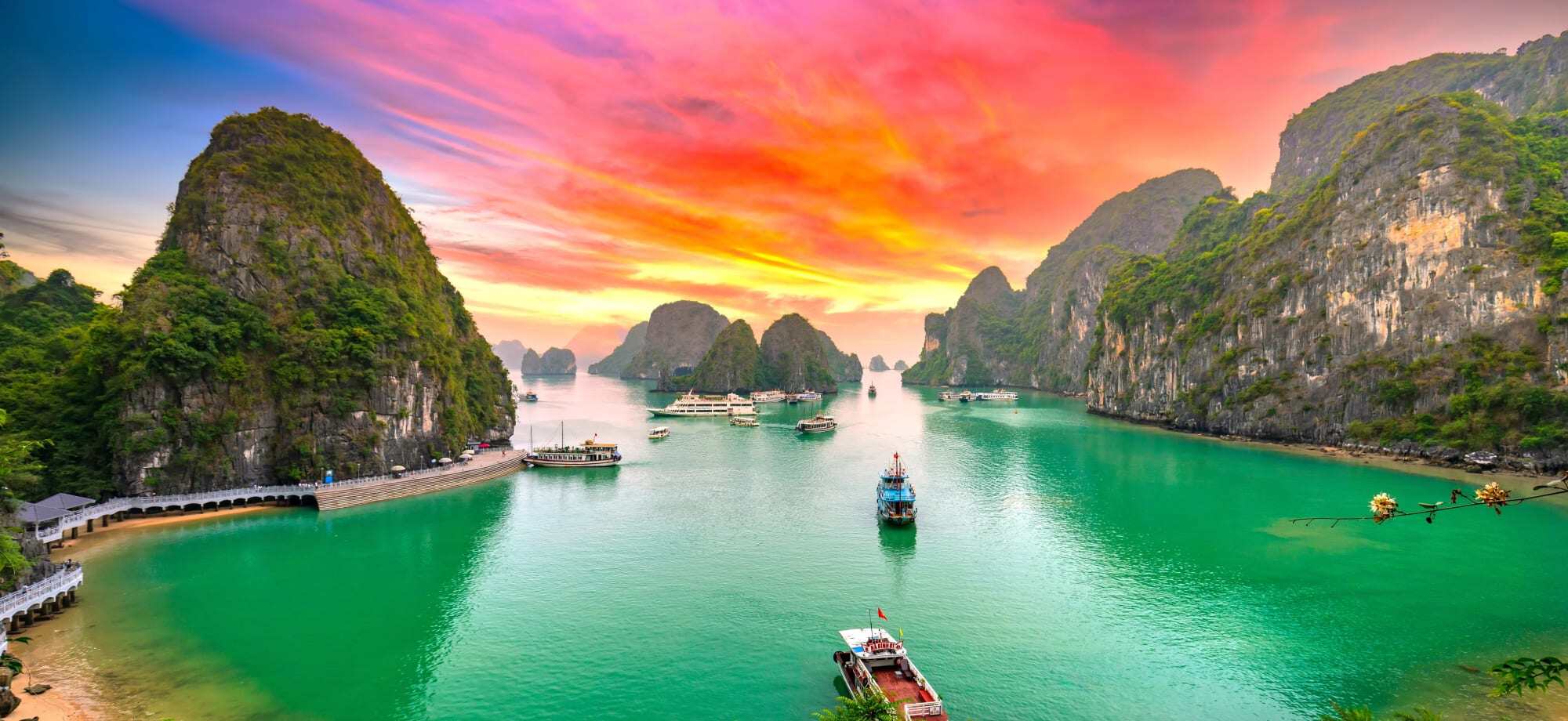 Ha Long Bay in Vietnam against a pink and orange sunset.