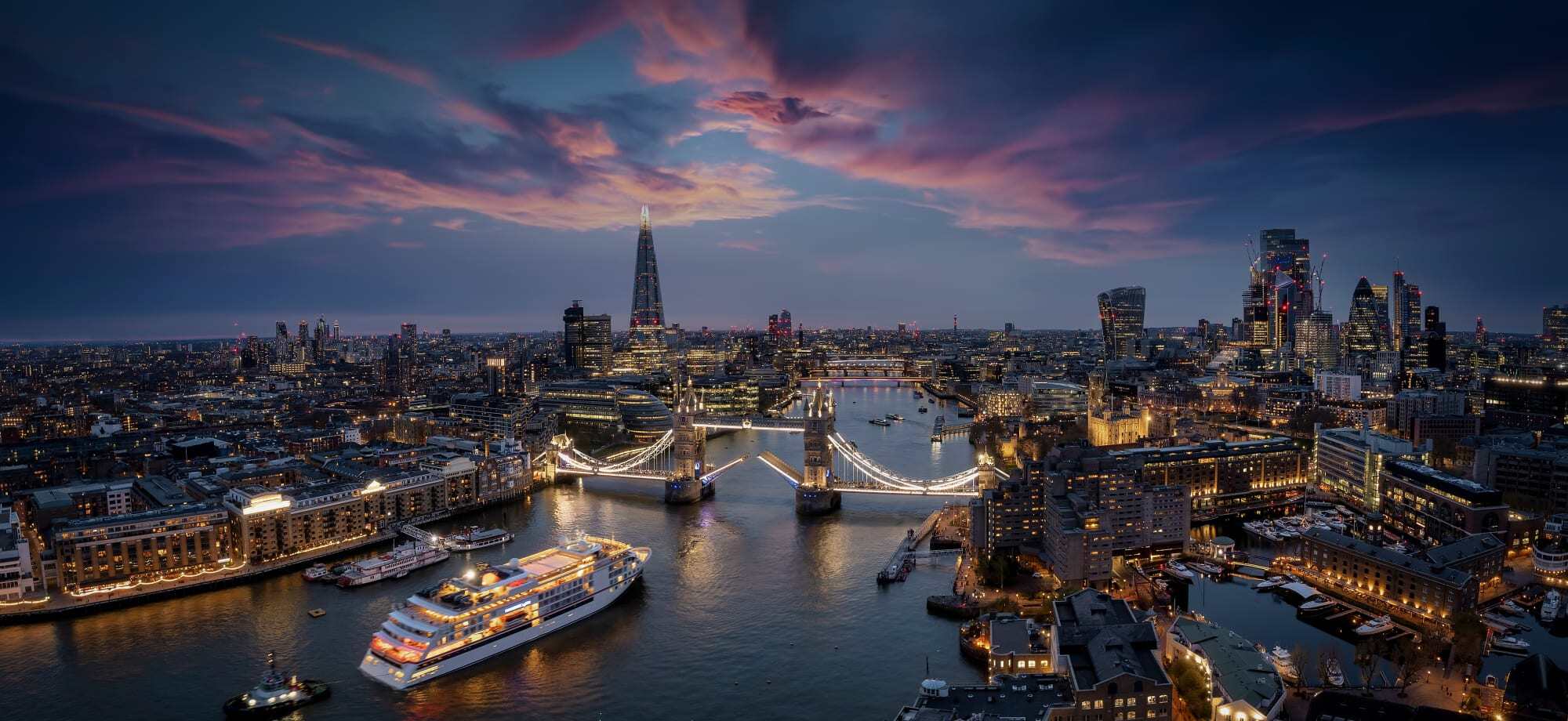 London is lit up at night and the River Thames sparkles.