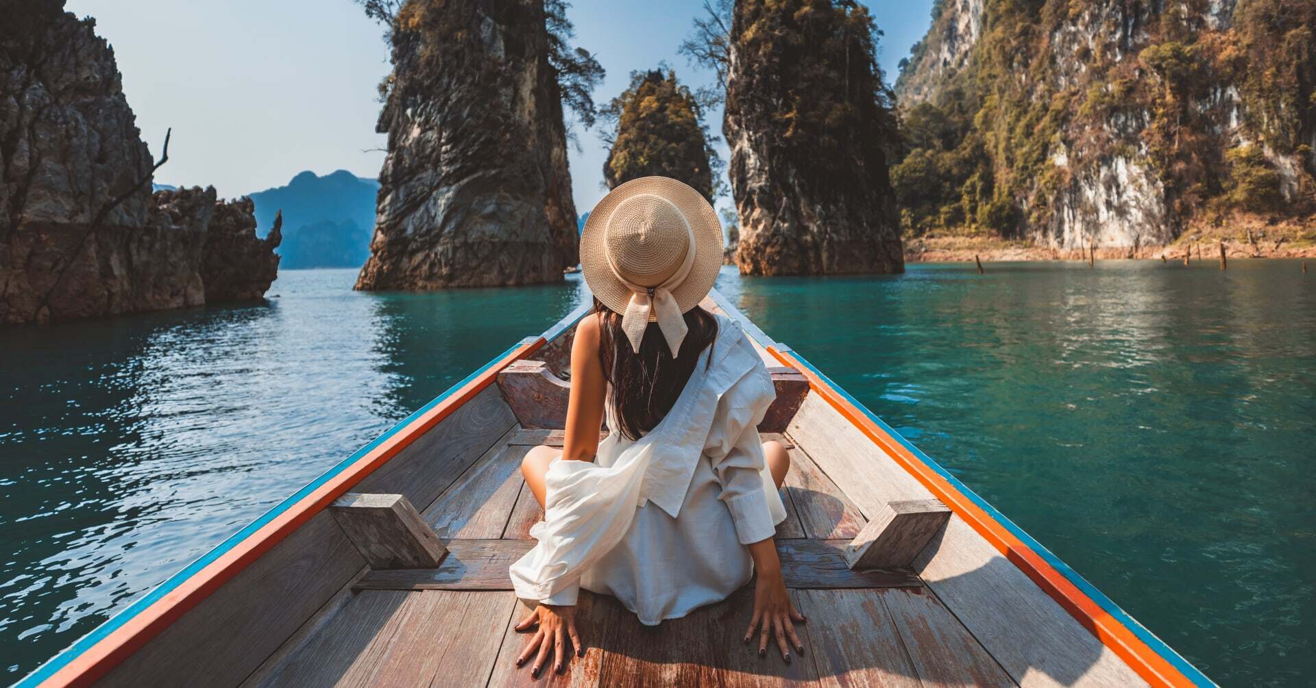 A lady sits on a traditional boat in Vietnam on a luxury vacation.