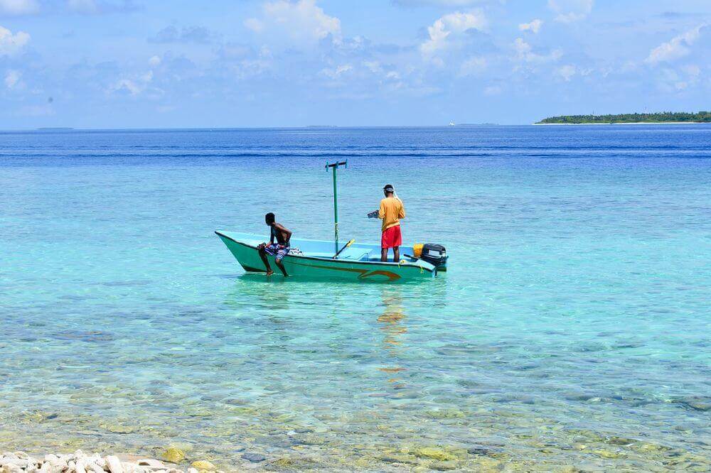 maldivian men fishing in the blue waters of the maldives